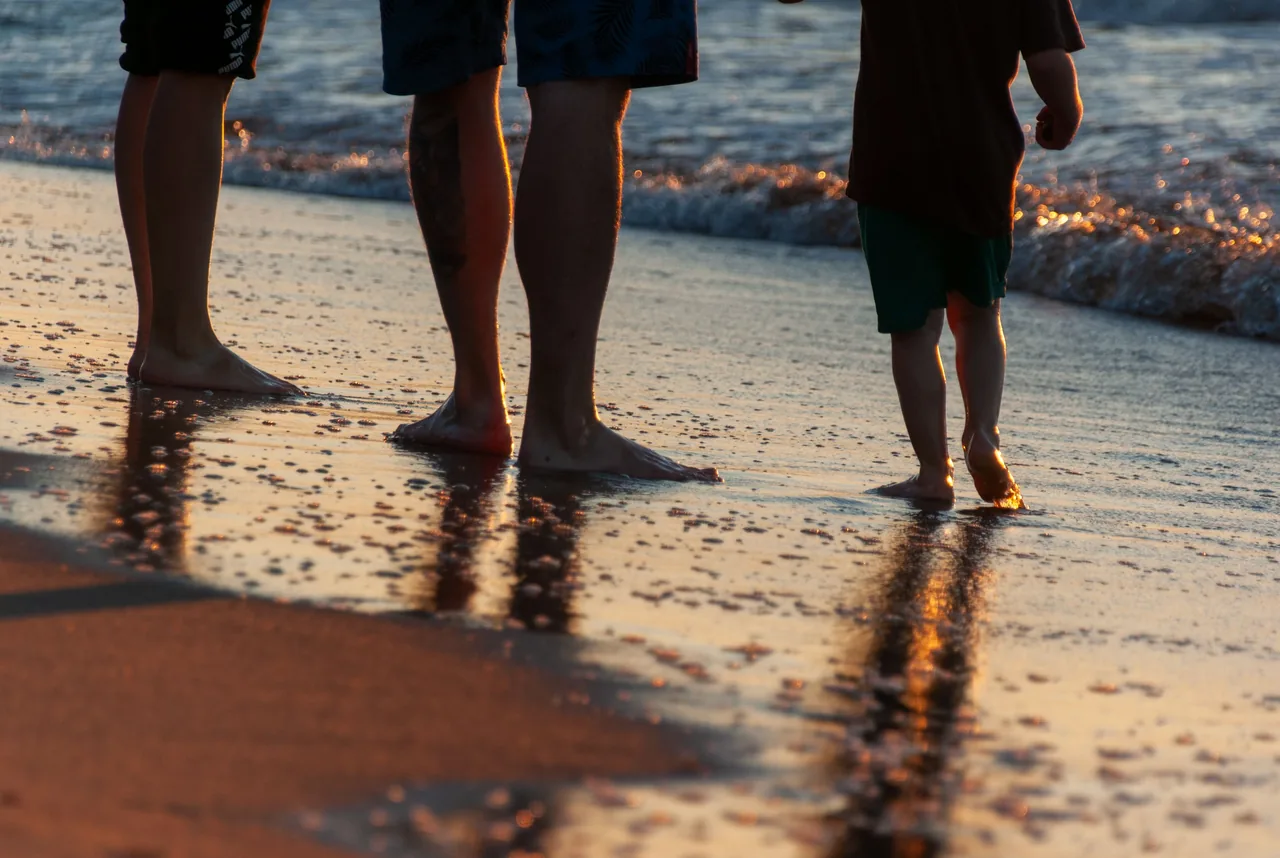 Silhouettes of a family walking along the beach at sunset, enjoying a peaceful moment together