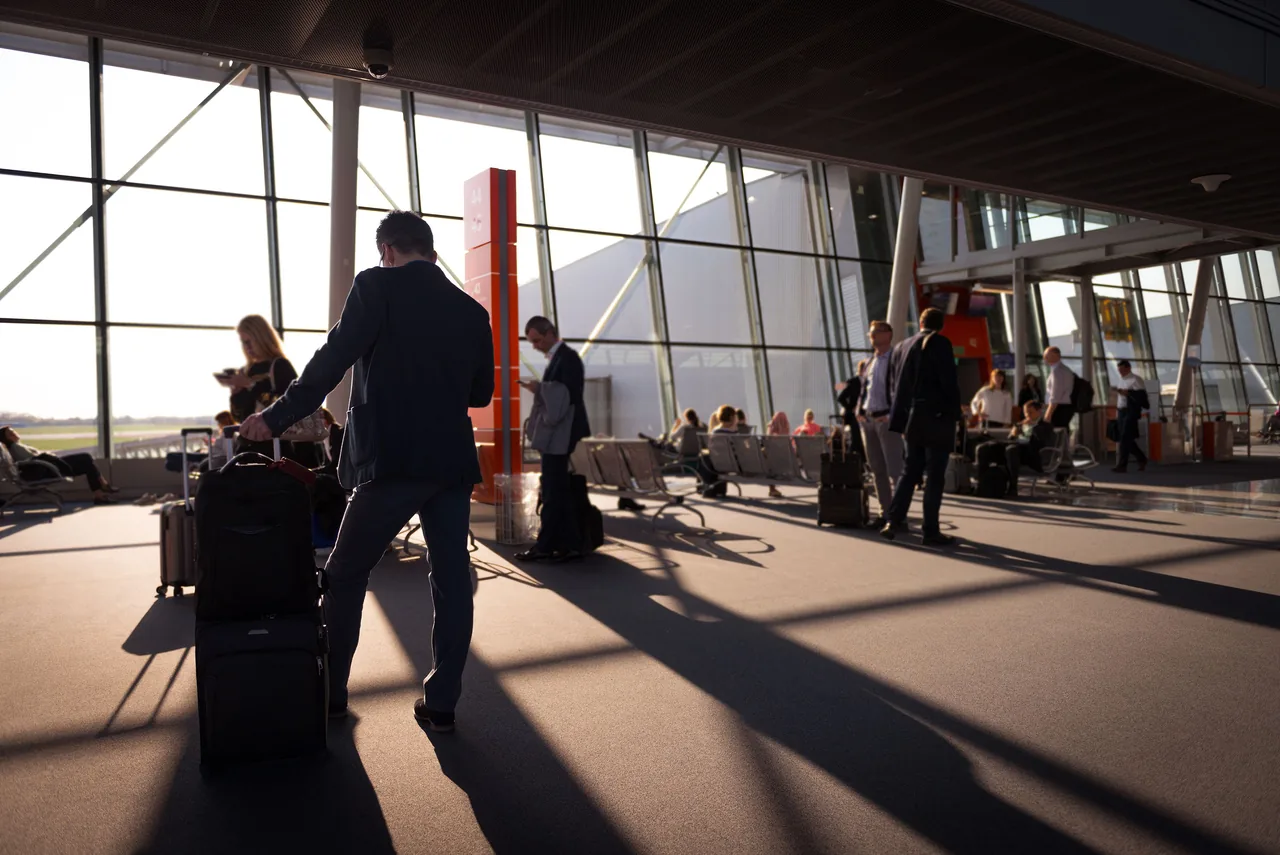 Travelers in a bustling airport terminal with carry-on luggage waiting for departure