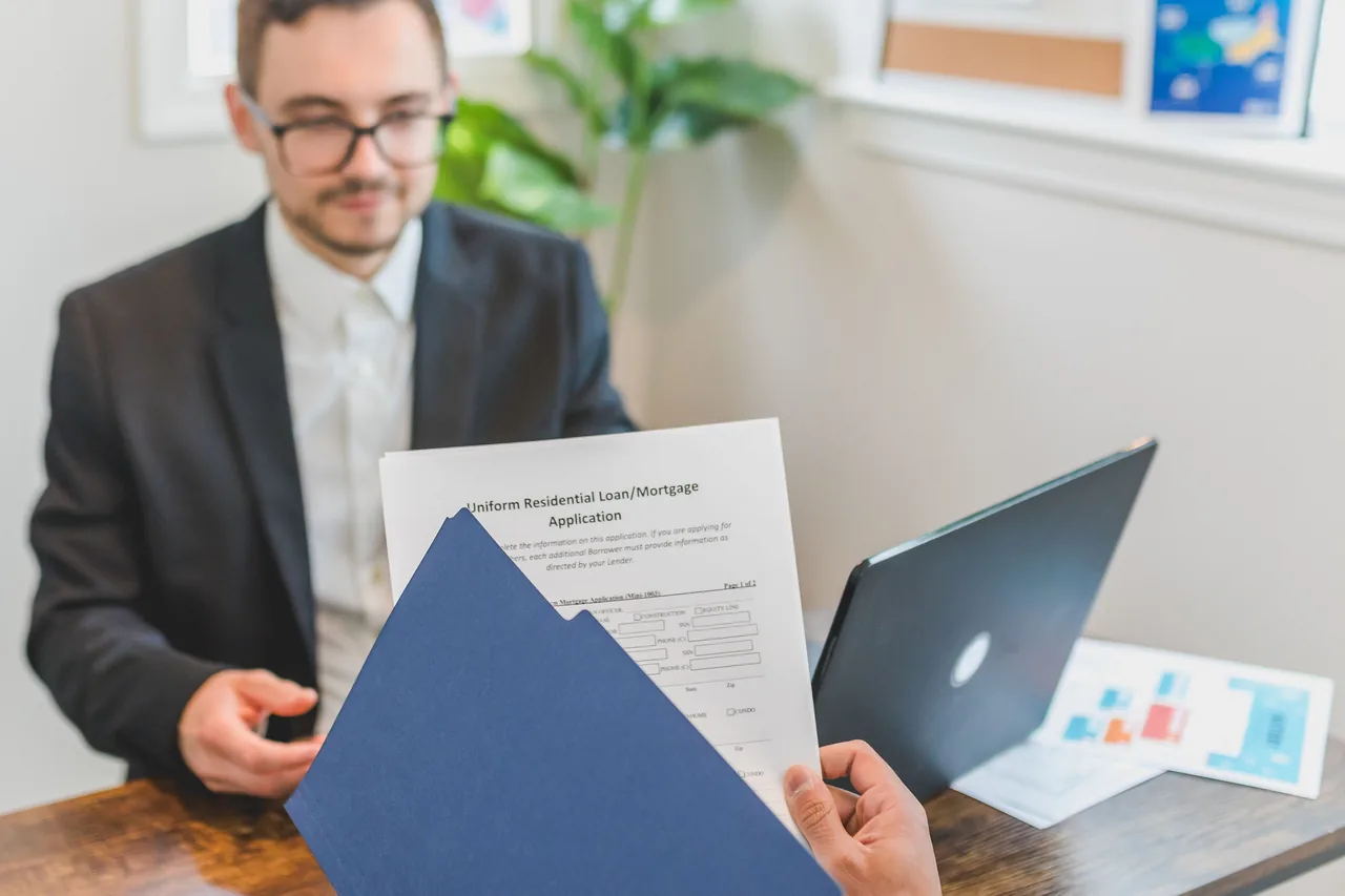 Mortgage broker and client discussing loan application with documents on table