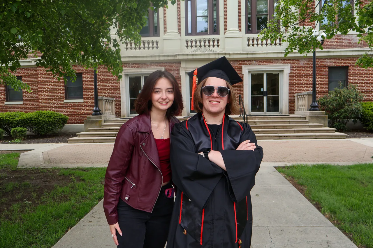 A man and woman celebrating graduation outdoors in front of a university building