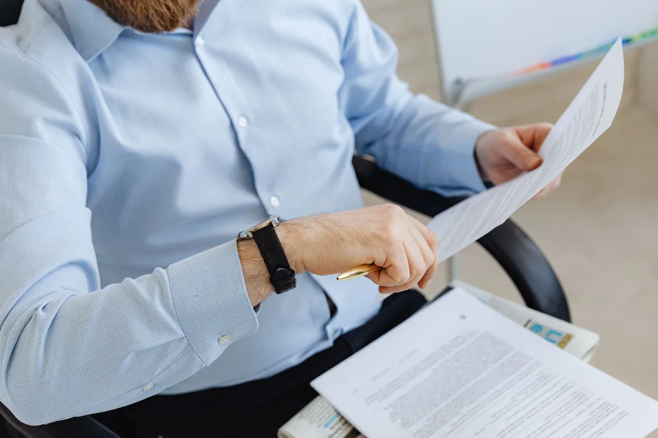 Businessman reviewing papers in office setting, highlighting analysis and attention to detail