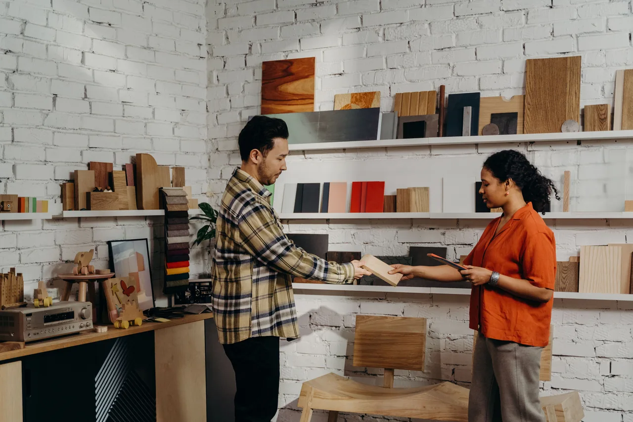 Two shoppers comparing wood and material samples in a modern home improvement store