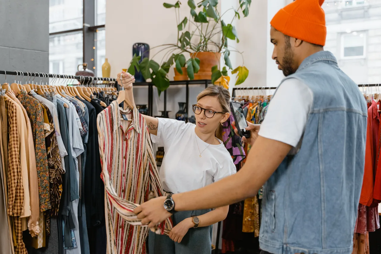 A woman helps a man choose a shirt in a modern clothing store