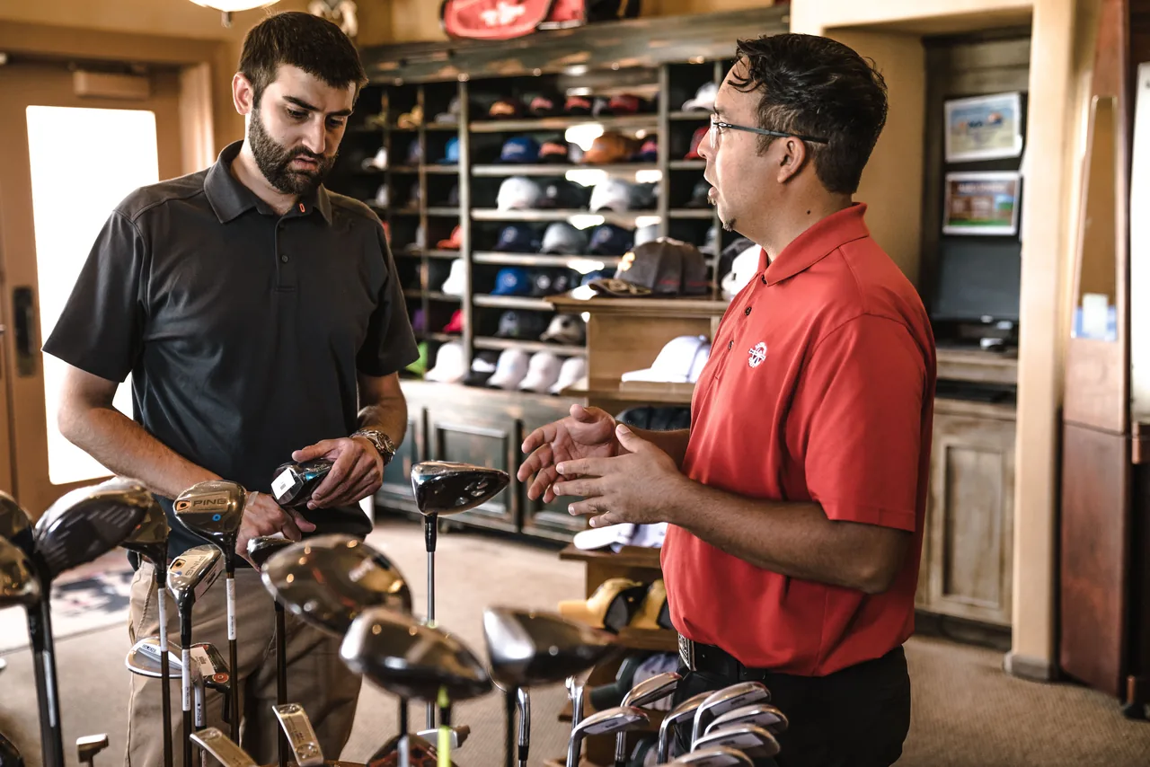 Customer receiving expert advice from salesman on golf equipment in a store