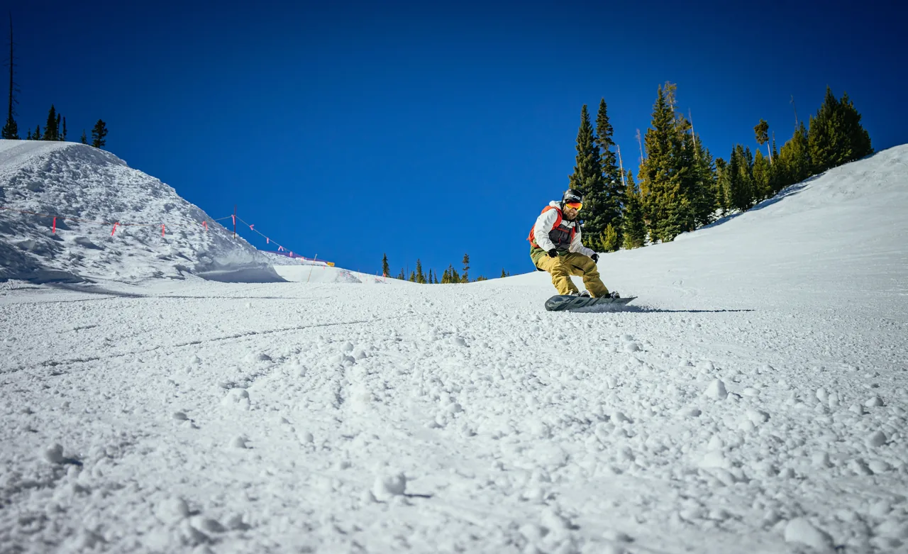 A snowboarder carves through fresh powder on a sunny winter day