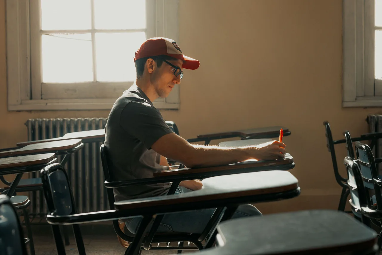 Single student studying in a bright classroom with sunlight streaming in, creating a focused atmosphere