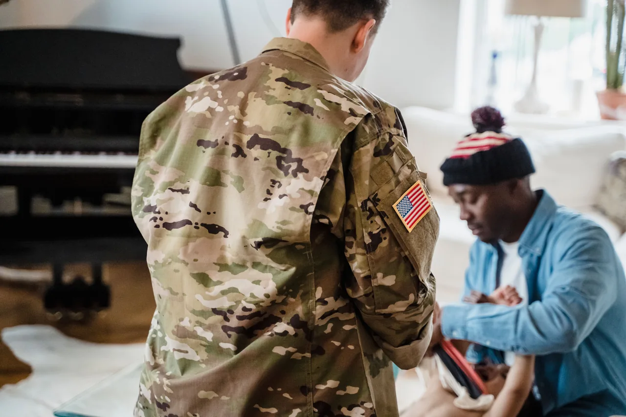 A soldier in camouflage uniform interacts with family at home, evoking themes of service and togetherness