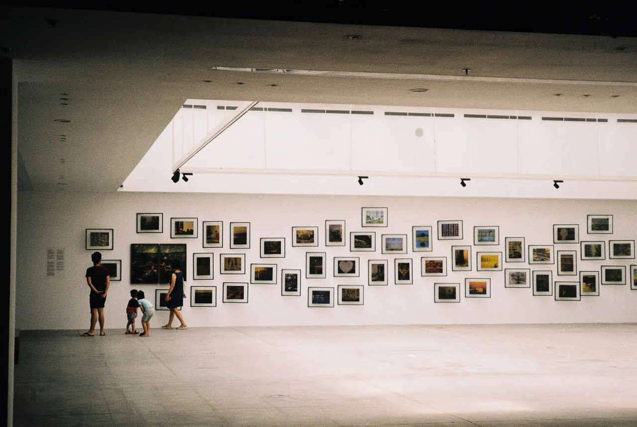 A family exploring an art exhibition in a modern gallery with framed artworks displayed on the wall