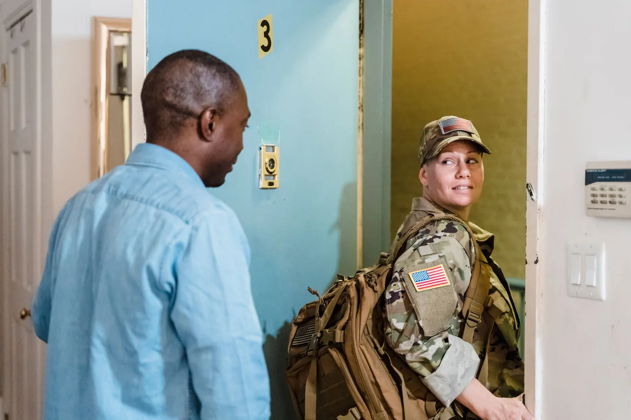 A soldier in uniform reunites with her partner at home, showcasing love and diversity