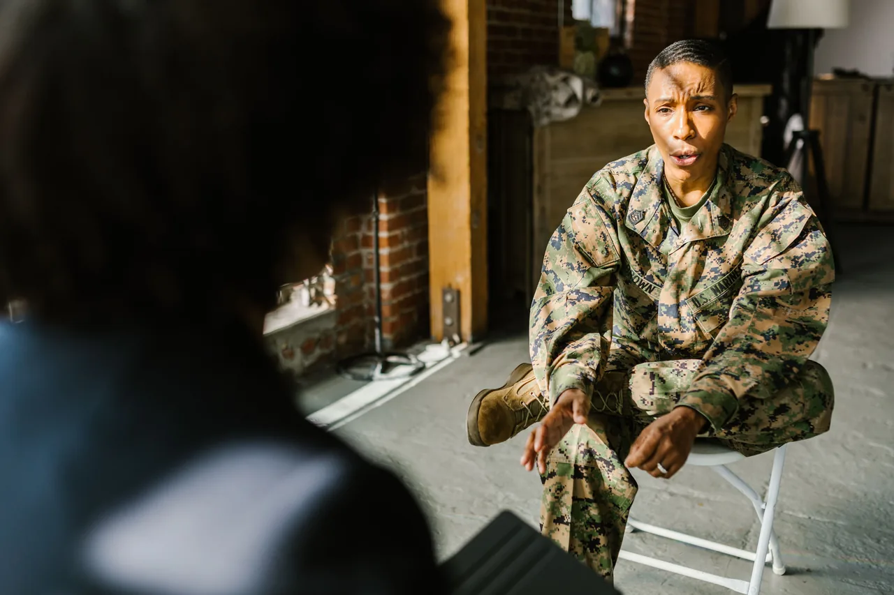 A soldier in military uniform during a therapy session indoors, discussing with a counselor